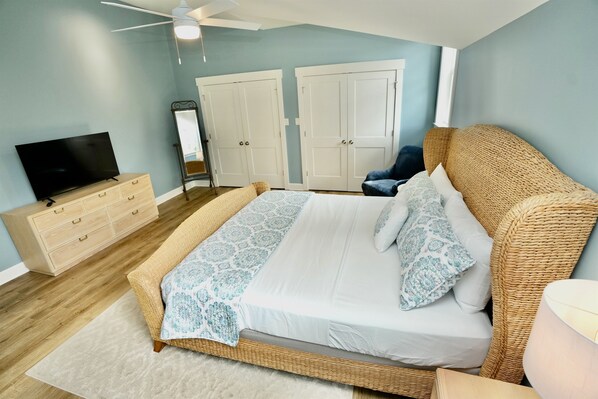 Un dormitorio con cama, cómoda, televisor, armario y ventilador de techo.