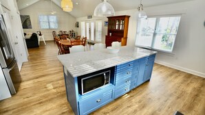 Une cuisine moderne dotée d’un grand îlot central, d’un plancher en bois et d’un coin repas avec une table et des chaises.