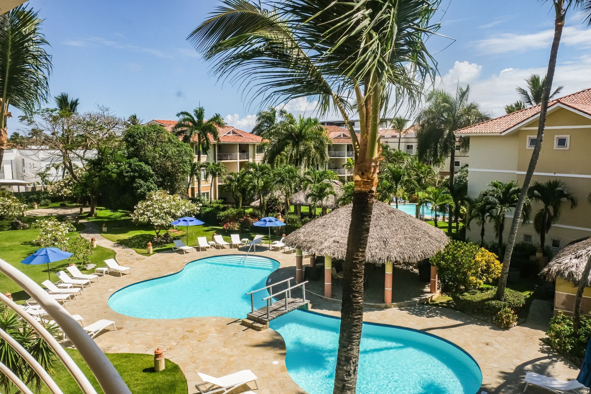 Un resort con piscina, sillas de descanso y palmeras.