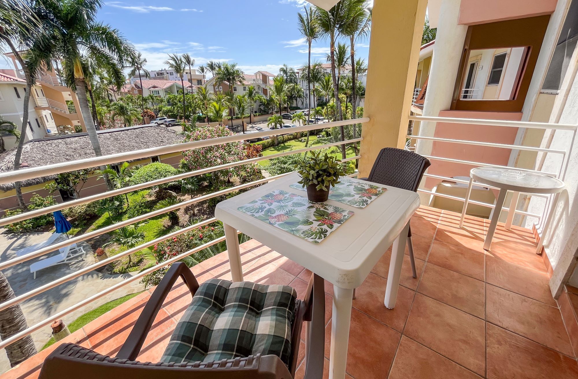 Ein Balkon mit Tisch, Stühlen und einer Topfpflanze.