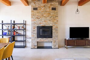 Una sala de estar con chimenea de piedra, una estantería, un televisor y un comedor.
