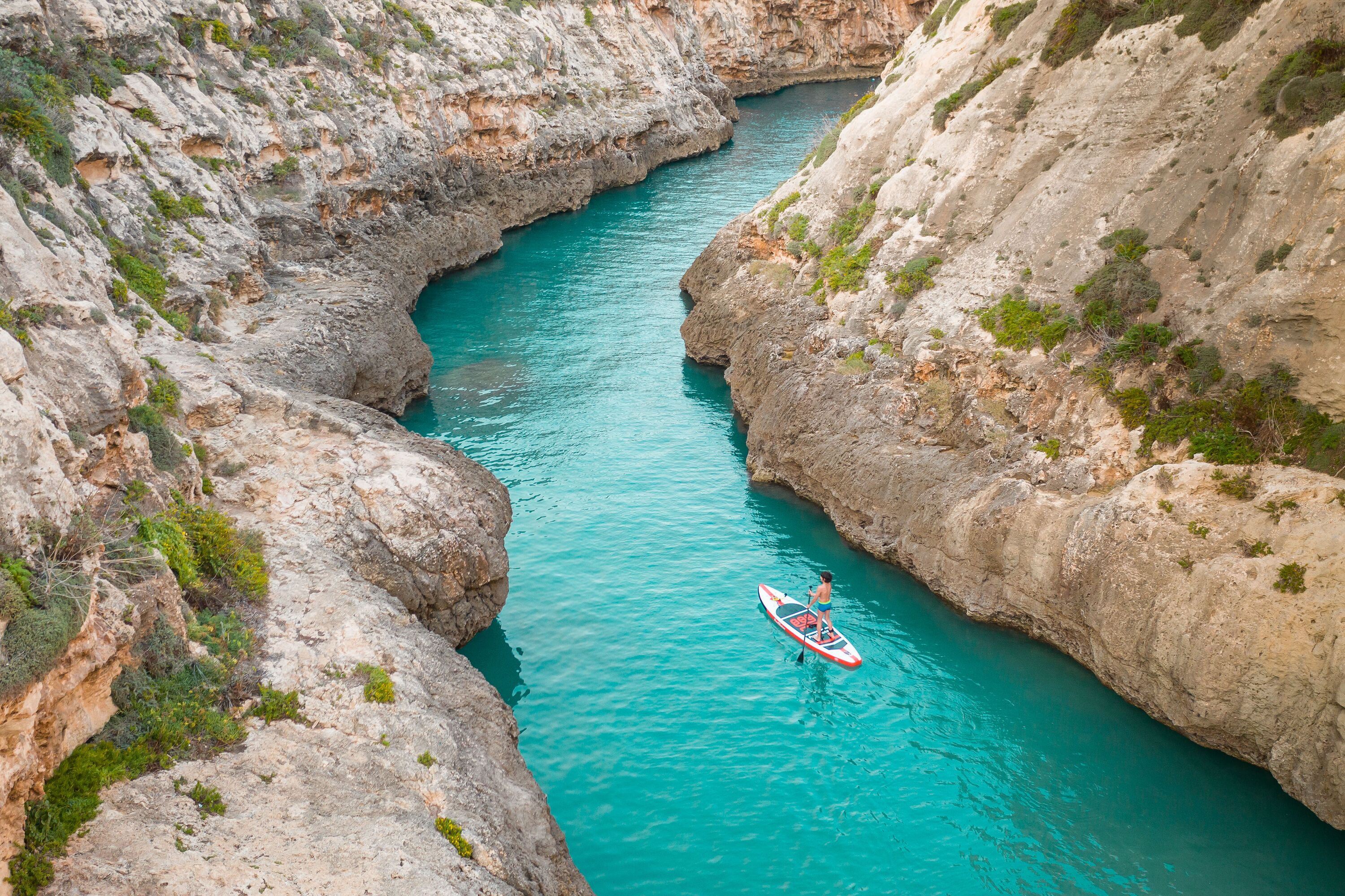 A narrow canyon with turquoise water and rocky cliffs.