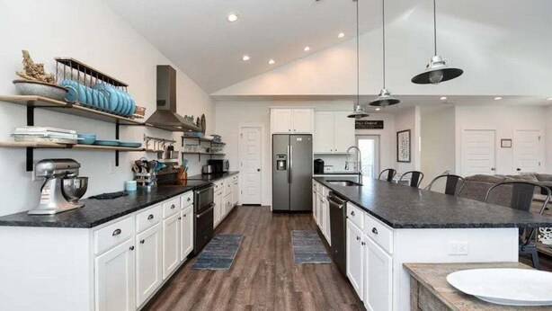 A modern kitchen with white cabinets, a central island, and a stainless steel refrigerator.