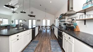 A spacious kitchen with a central island, white cabinetry, and a modern stove.