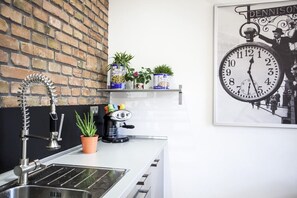 Eine Küche mit Spüle, einer Kaffeemaschine und Blumentöpfen auf einem Regal.