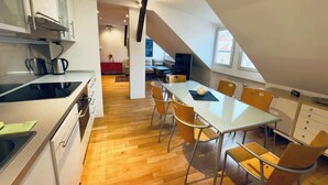 Une cuisine moderne avec un coin repas, un plancher en bois et une chambre à l’étage avec un plafond en pente.