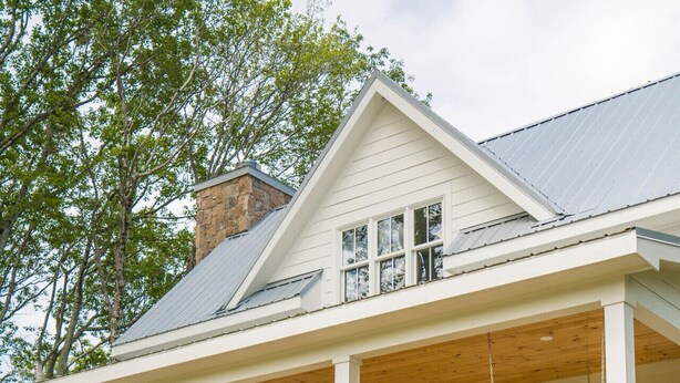 Una casa de dos pisos amb un porxo cobert, escales de pedra que condueixen a l'entrada i una petita zona de jardí.