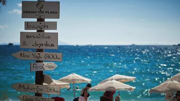 A signpost with directions to various destinations and amenities including beach, snacks, and drinks.