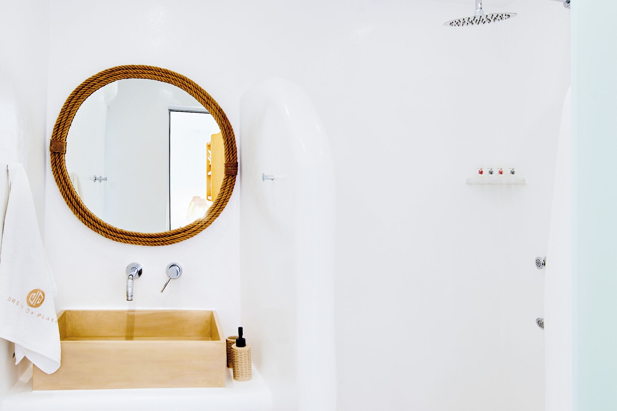 A bathroom with a round mirror, a wooden sink, and a towel hanging on the wall.
