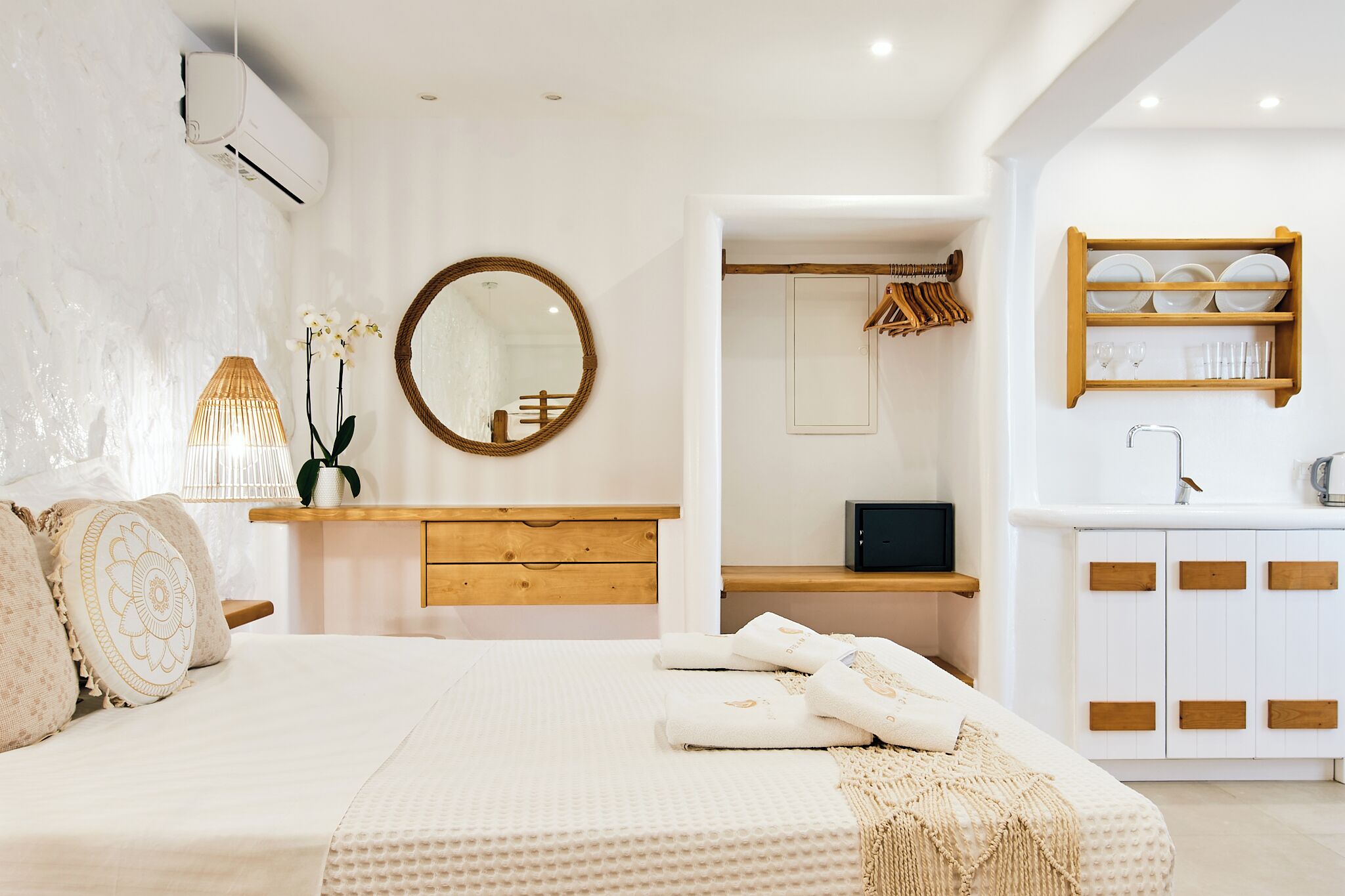 Ein Schlafzimmer mit Bett, Nachttisch, Spiegel, Kleiderschrank und einem Badezimmer mit Waschbecken und Ablagen.