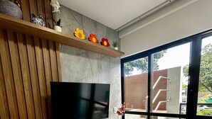 A modern living room with a wooden TV stand, a flat-screen TV, and a sliding glass door leading to an outdoor area. - Green Porto 06 (Ipojuca)