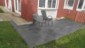 A patio area with a dark stone floor, a wooden bench, and a chair. - 1br-garden-parking-pets-10 Mins to Beach (Hornsea)