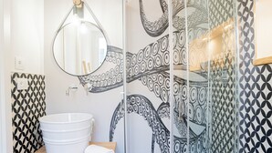 A bathroom with a white sink, a round mirror, and a patterned wall. - POLPO ROOM With Private Bath City Centre| PVT PARK (Moneglia)