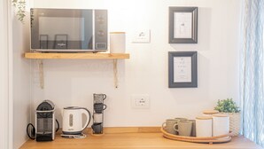 A kitchen with a microwave, kettle, coffee maker, and a shelf with framed certificates. - POLPO ROOM With Private Bath City Centre| PVT PARK (Moneglia)