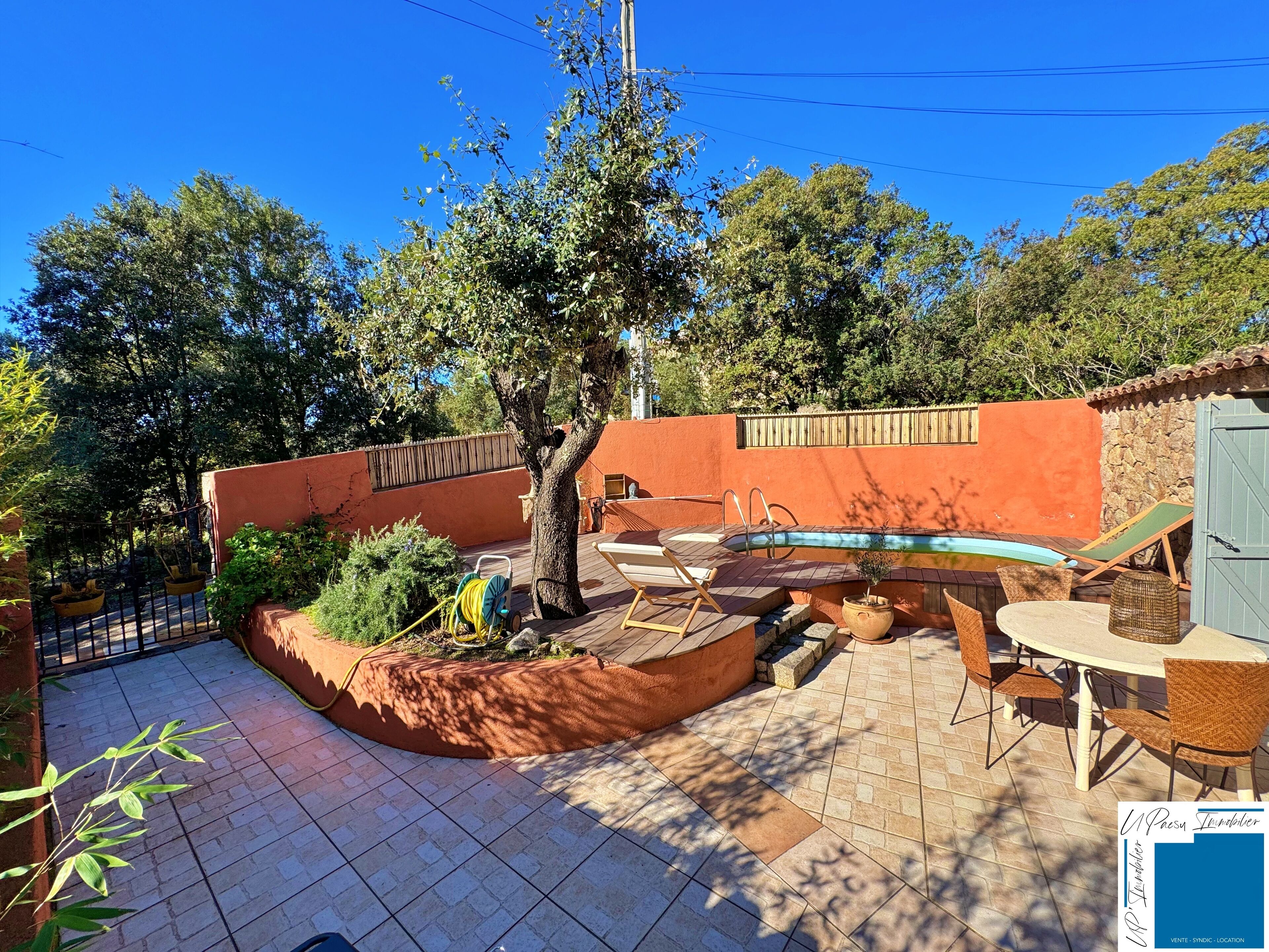 Un jardin avec une piscine, du mobilier d’extérieur et un arbre.