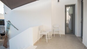 A modern, minimalist balcony with white furniture and a large umbrella. - Rivière Residence Paros   (Paros)