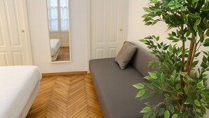 Una habitación con una cama, un sofá, un espejo y una planta en maceta.