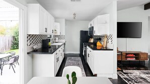 Eine moderne Küche mit weißen Schränken, einem schwarzen Kühlschrank und einem Essbereich mit Tisch und Stühlen.