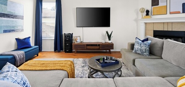 Ein Wohnzimmer mit Sofa, Couchtisch, Fernseher und Kamin.