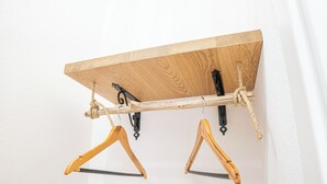 A wooden shelf with two wooden hangers suspended by black metal hooks.