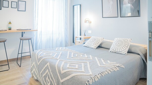 A bedroom with a bed, a desk, and a chair.