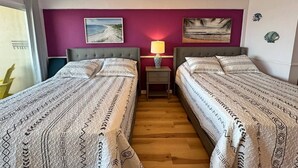 A room with two beds, a ceiling fan, a nightstand with a lamp, and artwork on the walls. - The Lidiya Room, right on the famous Daytona Beach. (Daytona Beach)