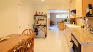 Une cuisine dotée de meubles en bois, d’un plan de travail en granit et d’un coin repas avec une table et des chaises en bois.