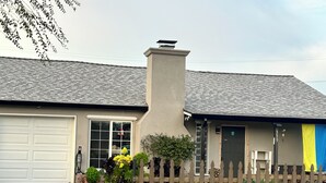 Une maison d’habitation avec un garage, une cheminée et une clôture en bois.