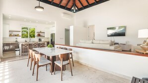 A spacious open-plan living area with a dining table, sofas, and a TV.