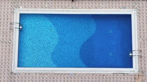 Ein Schwimmbecken mit einer gefliesten Terrasse darüber.