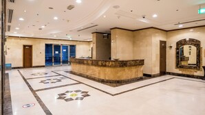 Eine Hotelhalle mit einer Rezeption, einem großen Spiegel und einem gemusterten Boden.
