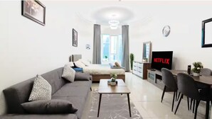Ein modernes Wohnzimmer mit einer Couch, einem Couchtisch und einem Fernseher, der 'NETFLIX' anzeigt.