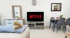 A hotel room with a bed, a TV, a desk, and a dining area. - Sunset Downtown Studio l Near Metro & Shops (Dubai)