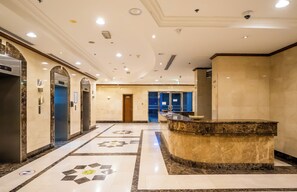 A hotel lobby with a reception desk, elevators, and a patterned floor. - Sunset Downtown Studio l Near Metro & Shops (Dubai)