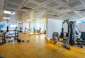 A gym with various exercise equipment, large windows, and a wooden floor. - Sunset Downtown Studio l Near Metro & Shops (Dubai)