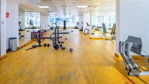 Ein Fitnessstudio mit Trainingsgeräten, Spiegeln und einem Holzboden.