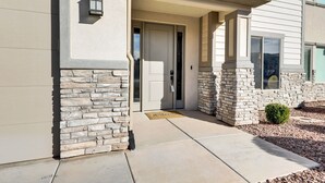 A building with a stone facade, a front door, and a small garden area. - Stunning Townhome in Zion Village with private hot tub and lazy river (Hurricane)