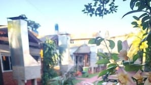 A pathway leading to a building with a red exterior, surrounded by greenery and flowers. - El Rosedal Cataratas / Apartment - 2 levels (Puerto Iguazú)
