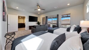 A hotel room with two beds, a ceiling fan, a flat-screen TV, a balcony with a view, and a desk with a chair. - Stunning townhome with premiere resort amenities, lazy river and private hot tub (Hurricane)