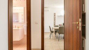 A doorway leading to a bathroom with a sink and mirror, and a dining area with a table and chairs. - Grace s House in Pisa (Pisa)