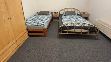 A room with two single beds, a wooden wardrobe, and a radiator.