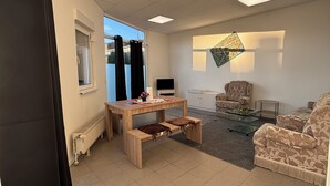 A room with a wooden table, benches, a sofa, and a television.