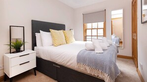 A bedroom with a bed, bedside table, lamp, and a window. - Bright&Cosy Flat near Scottish Gallery (Edinburgh)