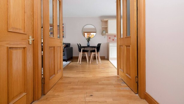 A hallway with wooden doors leading to a dining area with a table and chairs. - Bright&Cosy Flat near Scottish Gallery (Edinburgh)