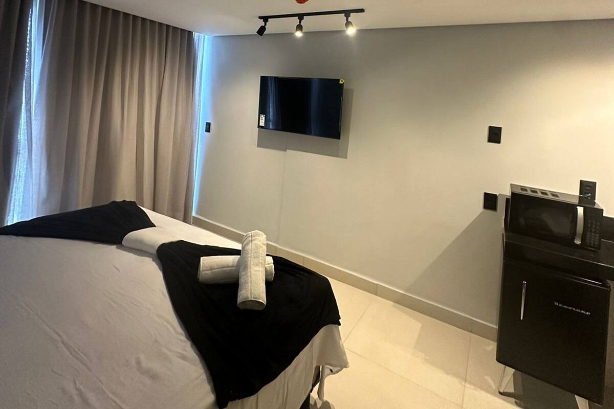 Ein Hotelzimmer mit einem Bett, einem Flachbildfernseher, einer Mikrowelle, einem kleinen Schrank und einer Deckenleuchte.