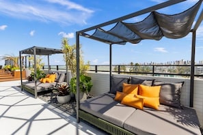 A rooftop terrace with a seating area, plants, and a city skyline view. - Altagarden Beira Mar (João Pessoa)
