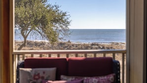 Blick vom Balkon mit rotem Sofa, Baum und Meer.