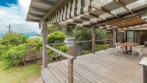 A wooden deck with a pergola, outdoor seating, and a view of the ocean. - Two Many Birds - Seal Rocks (Seal Rocks)