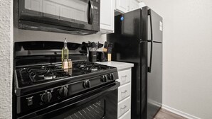 Una cocina con estufa negra, microondas y refrigerador negro.