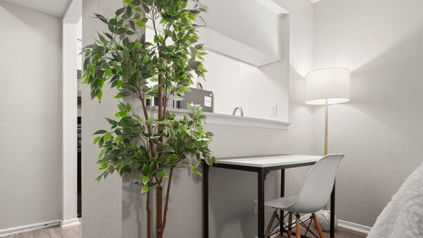 Un rincón comedor pequeño con una mesa, una silla, una planta en maceta y una lámpara de pie.